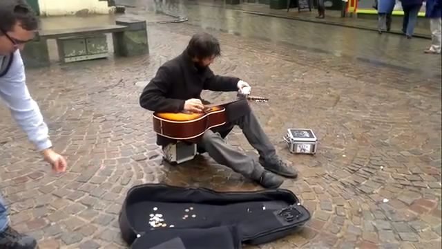 Уличный музыкант играет на гитаре флягой для алкоголя