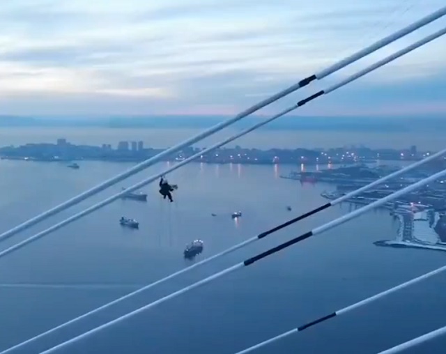 Альпинист из Владивостока очищает от наледи мост на остров Русский